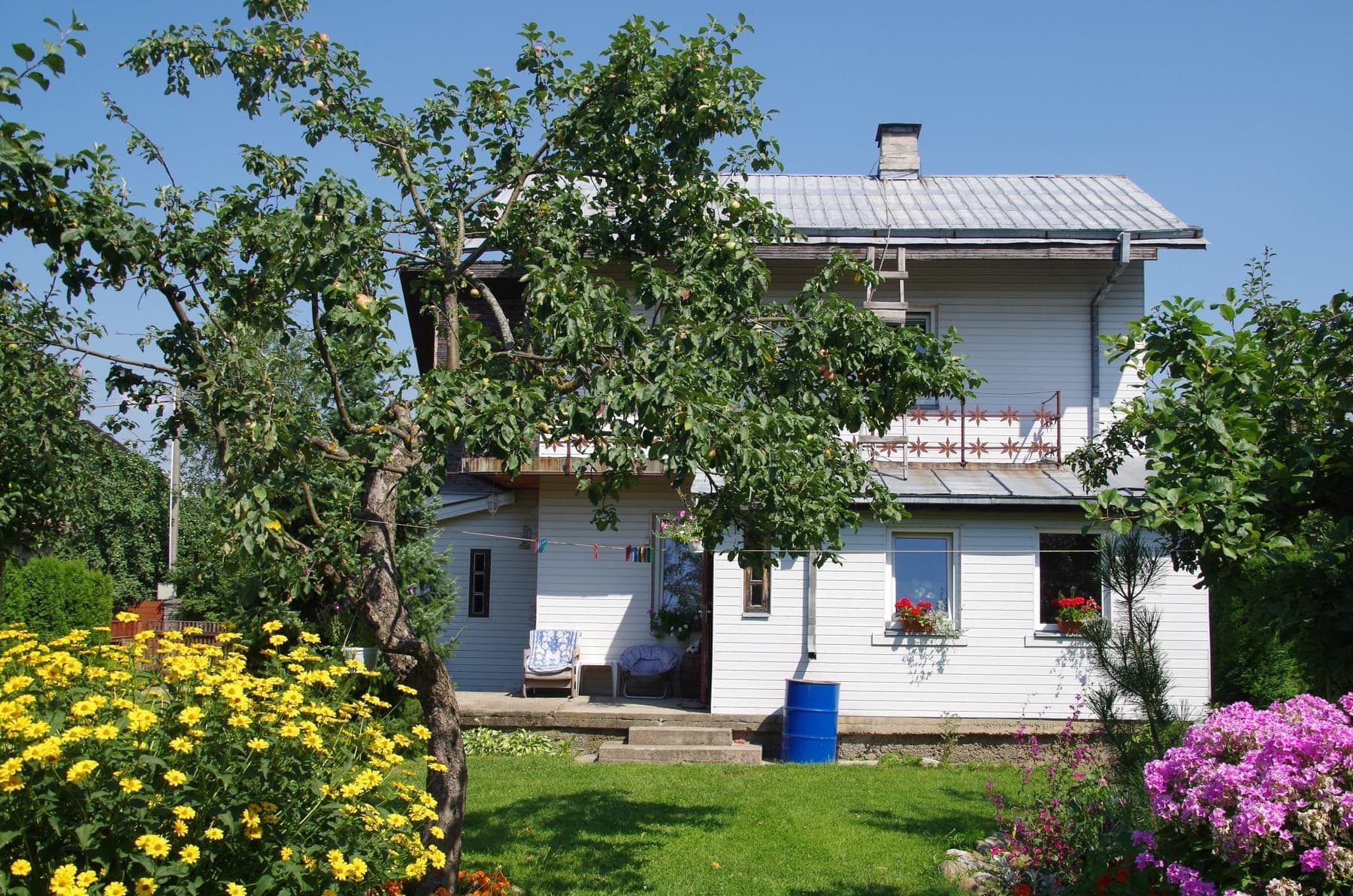 Casa de dos pisos rodeada de un jardín con flores