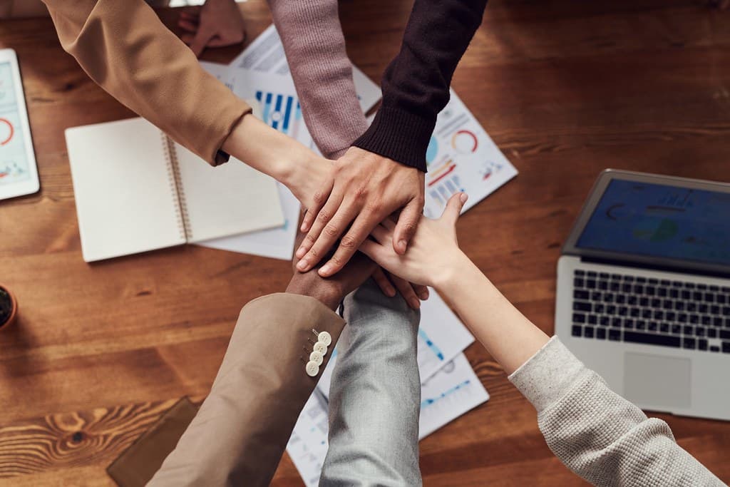 Manos de un equipo de trabajo unidas sobre una mesa